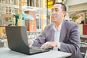 Asian Businessman typing on Notebook or Laptop Computer