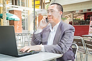 Asian Businessman use Wireless Digital Smartphone and Laptop or