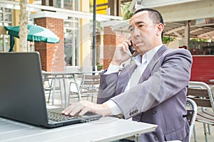 Asian Businessman use Wireless Digital Smartphone and Laptop or