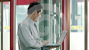 Asian businessman using laptop computer in hallway