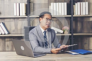 Asian Businessman using laptop at office desk. Man hands typing computer keyboard reading financial graph chart Planning analyzing