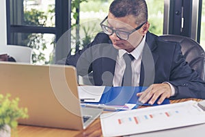 Asian Businessman using laptop at office desk. Man hands typing computer keyboard reading financial graph chart Planning analyzing