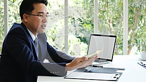 Asian Businessman using laptop at office desk. Man hands typing computer keyboard reading financial graph chart Planning analyzing