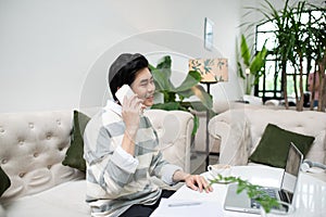 Asian businessman using mobile phone while working with laptop o