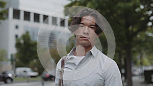 Asian businessman using mobile while posing on street