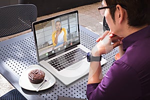 Asian businessman video conferencing with african american businesswoman through laptop in office
