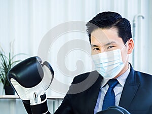 Asian Businessman wearing suit and hand wearing boxing gloves in office