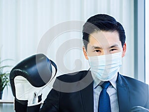 Asian Businessman wearing suit and hand wearing boxing gloves in office