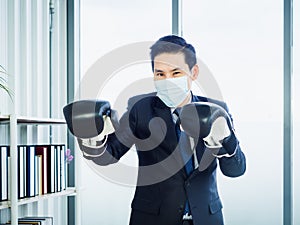 Asian Businessman wearing suit and hand wearing boxing gloves in office