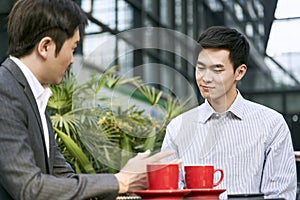 Asian businessmen discussing business at outdoor cafe