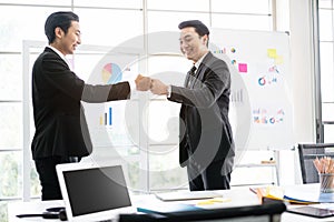 Asian businessmen fist bump for the teamwork of business mergers and acquisitions for successful negotiation. Two businessmen.