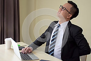 Asian businessmen in a suit working hard and feeling painful touching back with pained expressionat after long working hours photo