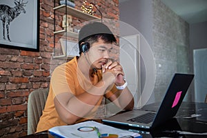 Asian businessmen is using notebook computers and wear headphones for online meetings and working from home