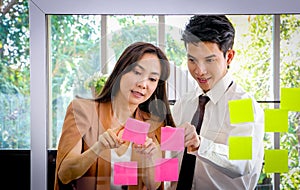 Asian businessmen and women looking and writing post-it notes for brainstorming