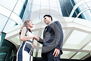 Asian businesspeople handshake in front of high rise building