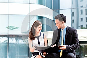 Asian businesspeople working outside on documents