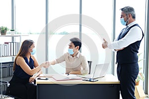 Asian businessswoman shake hands with businessman and Caucasian Senior boss Thumbs up for good idea in job. Businesspeople is