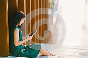 Asian businesswoman or college student using digital tablet during sunset, modern office or library scene