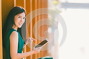 Asian businesswoman or college student using and pointing at digital tablet during sunset, at modern office or library