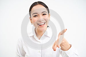 Asian businesswoman extends hand for handshake, team leader introduces herself and smiles friendly, stands confident on