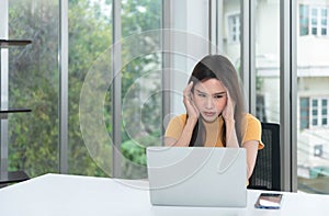 Asian businesswoman feeling stressed as he looks at earning money on laptop computer