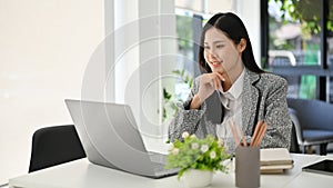 Asian businesswoman hands on chin, thinking new ideas for her project, working in the office