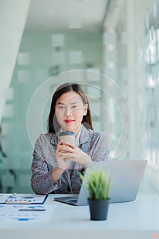 Asian businesswoman holding a cup of coffee working on investment projects and financial accounting planning strategies. Businessm