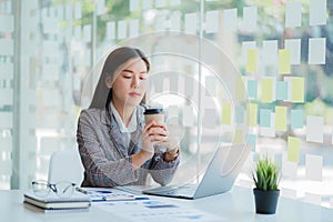 Asian businesswoman holding a cup of coffee working on investment projects and financial accounting planning strategies. Businessm