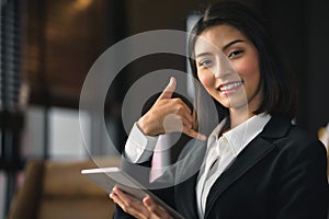 An Asian businesswoman holding a tablet inviting her to come back
