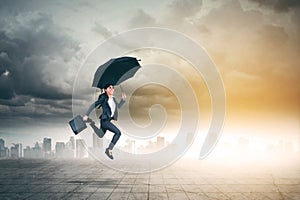 Asian businesswoman jumps with umbrella