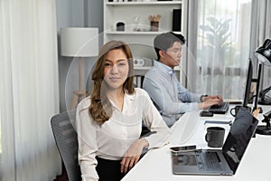 Asian businesswoman looking camera pose on blurry man in casual day. Infobahn.