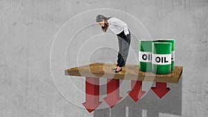 Asian businesswoman looking down with an oil barrel