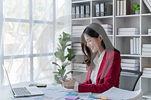 Asian businesswoman in office happy and cheerful during using smartphone and working