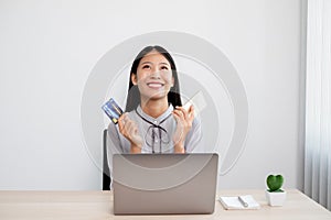 The Asian businesswoman`s hand is holding a credit card and using a smartphone and laptop for online shopping internet payment in
