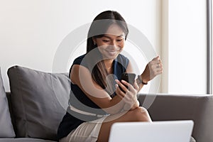 Asian businesswoman sit on couch in office using smartphone