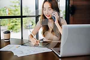 Asian businesswoman sitting at cafe calling mobile phone talking with customer