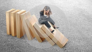 Asian businesswoman sitting on topple wooden block