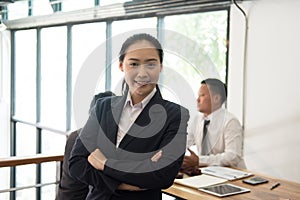 Asian businesswoman smiling at camera while colleagues have meet