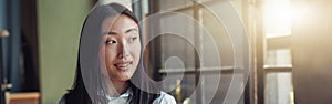 Asian businesswoman standing at office with phone and looking at window