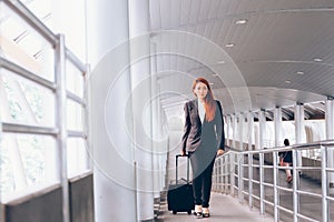 Asian businesswoman taking a luggage and walking towards the platform way - business travel and commuting people concept