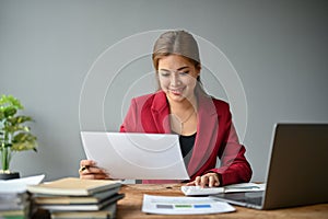 An Asian businesswoman using a calculator to plan budgets and working on financial reports