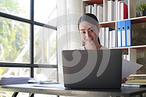 Asian Businesswoman Using laptop computer and working at office with calculator document on desk, doing planning