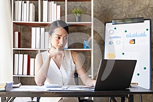 Asian Businesswoman Using laptop computer and working at office with calculator document on desk, doing planning