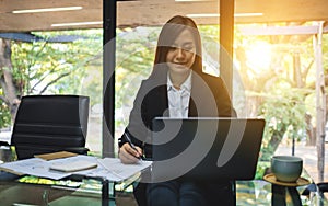 An asian businesswoman using and typing on laptop while working in office