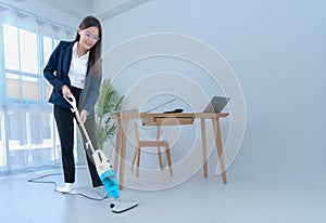 Asian businesswoman using a vacuum cleaner to clean