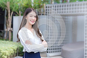 Asian businesswoman wearing a white shirt and standing with her arms crossed smile while working outdoors the office