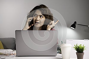 Asian businesswoman work at home with laptop and talking on smartphone and smiling. Female working on computer and using cell mobi