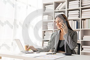 Asian businesswoman working at home office and analyzing financial documents and calculator, phone, laptop