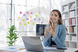 Asian businesswoman working at home office and analyzing financial documents and calculator, phone, laptop