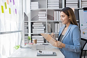 Asian businesswoman working at home office and analyzing financial documents and calculator, phone, laptop